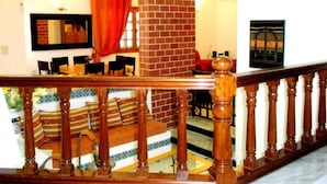 A staircase with wooden balusters, a brick wall, and a dining area with chairs and a table.