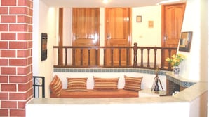 A cozy living area with a brick wall, wooden cabinets, a cushioned bench, and a tiled backsplash.