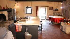 A kitchen with a central island, a stone fireplace, and a dining area with a table and chairs.
