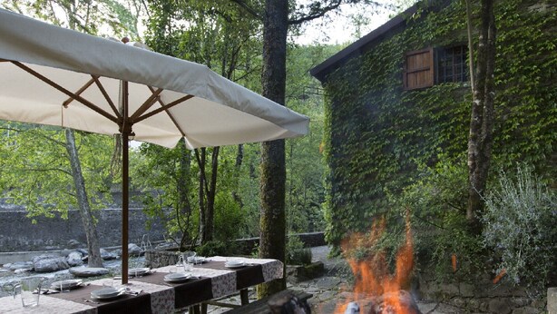 An outdoor dining area with a fire pit, tables, and an umbrella.