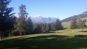 A golf course with a clear view of snow-capped mountains in the background.