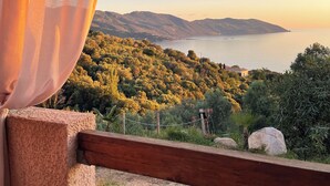 A balcony with a view of a mountainous landscape and a body of water during sunset.
