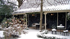 A snow-covered patio with outdoor seating and a covered area.