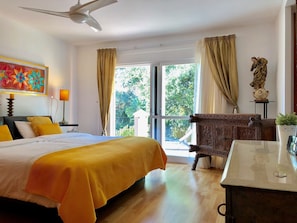 Ein Hotelzimmer mit einem Bett, einem Schreibtisch, einem Sessel, einer Statue und einem Vorhangfenster.