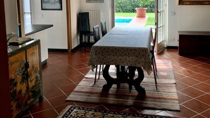 Un coin repas avec une table dressée pour quatre personnes, un tapis à motifs et une vue sur l’extérieur par une porte.