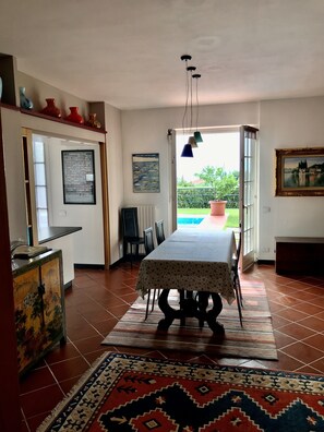 A dining area with a table set for four, a patterned rug, and a view of the outdoors through a door. - Ground floor apartment lake view  (albisano torri del benaco)