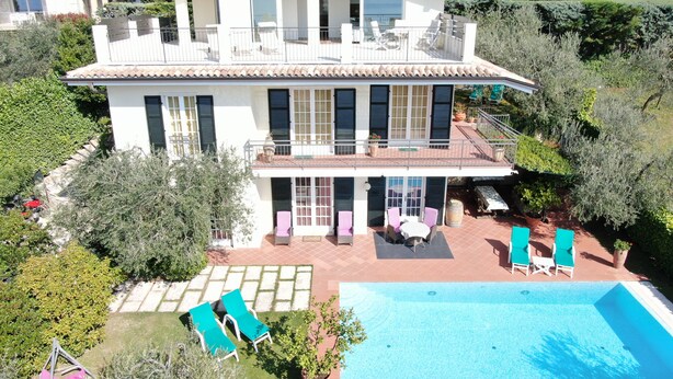 Une maison à deux étages avec une piscine, un espace salon extérieur et un jardin.