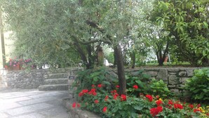 Un escalier en pierre mène à un mur de pierre orné de fleurs rouges et de feuillage vert.
