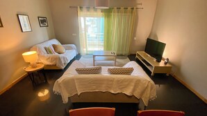 A hotel room with a bed, a sofa, a TV, and a small table. - Apartment in residence 50 meters from the beach and 500m from Miramar Golf (Vila Nova De Gaia)