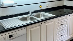 A modern kitchen with white cabinetry, a black countertop, and a Bosch dishwasher. - Apartment in residence 50 meters from the beach and 500m from Miramar Golf (Vila Nova De Gaia)