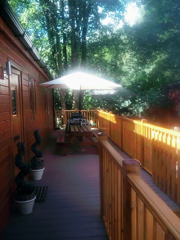 A wooden deck with a table and chairs, surrounded by a wooden railing, and potted plants.