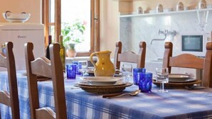 A dining area with a table set for four, wooden chairs, a blue and white checkered tablecloth, a yellow pitcher, and blue glassware. - REFINED RUSTIC WITH A TASTE COUNTRY CHIC IMMERSED IN AN OASIS OF PEACE (STAZZEMA)