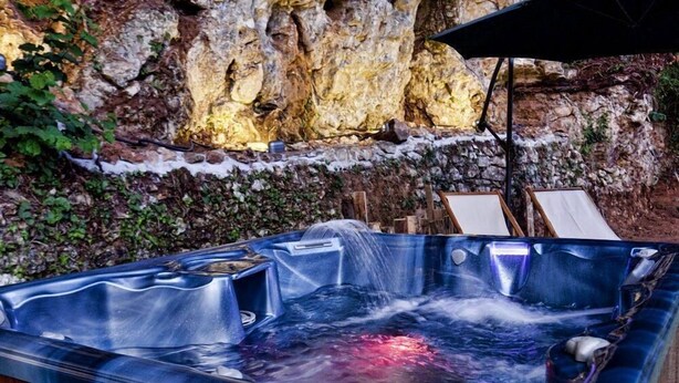 A hot tub with a waterfall feature, surrounded by a rocky wall and greenery. - REFINED RUSTIC WITH A TASTE COUNTRY CHIC IMMERSED IN AN OASIS OF PEACE (STAZZEMA)