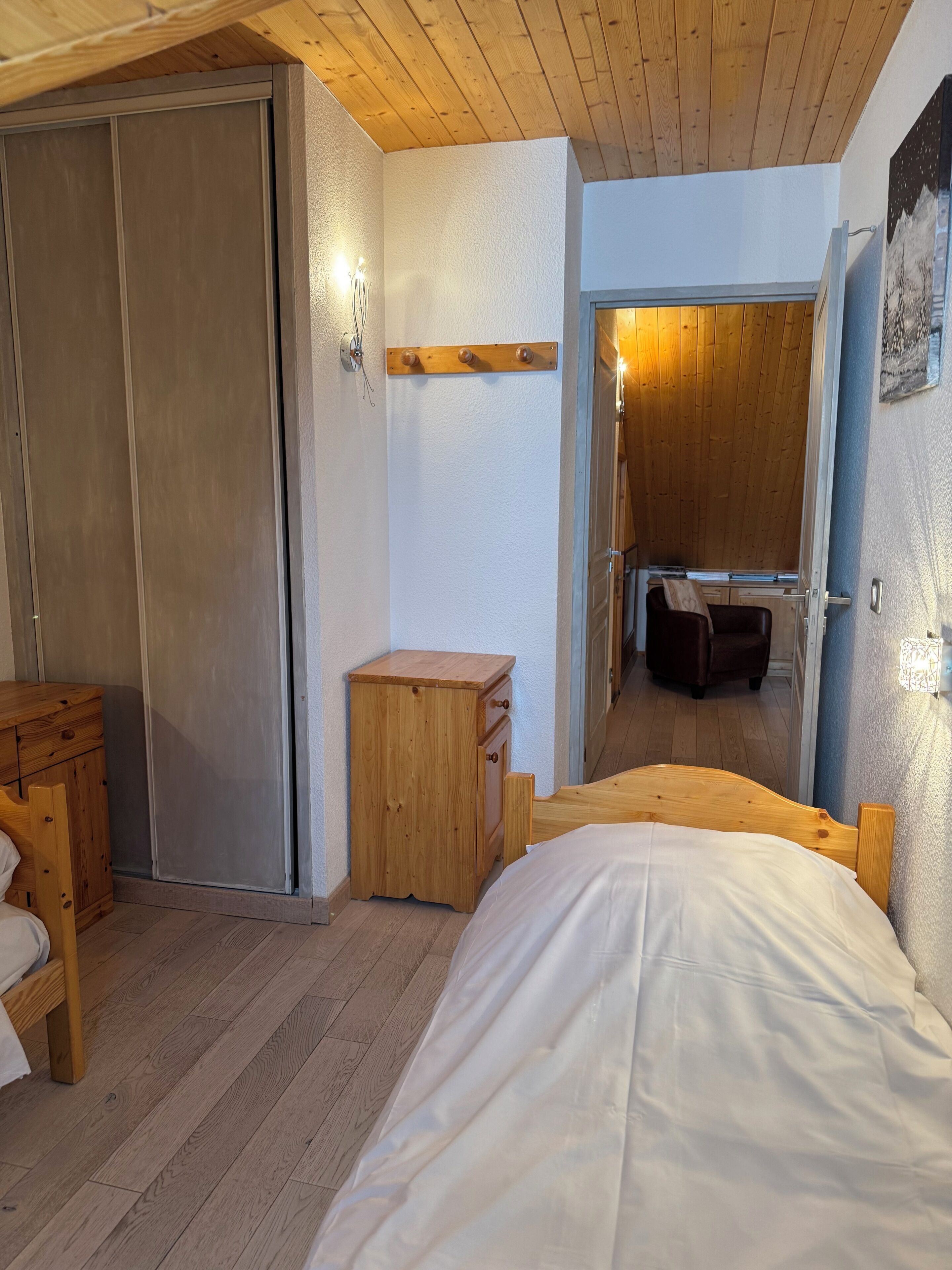 Une chambre à coucher avec un lit en bois, une table de chevet en bois, une armoire et un petit meuble en bois.