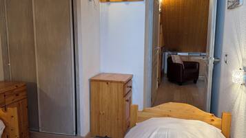 Une chambre à coucher avec un lit en bois, une table de chevet en bois, une armoire et un petit meuble en bois.