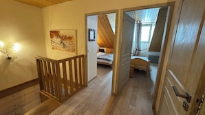 En trætrapper fører op til et soveværelse med skråvægge og en seng.