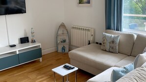 Una sala de estar moderna con un sofá, una mesita, un televisor y un estante decorativo.
