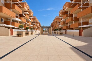 A modern apartment complex with multiple balconies, a central open space, and a clear sky.