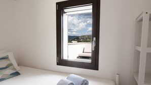 A bedroom with a bed, a window with a view of a balcony, and a towel on the bed. - Sea views in a tranquil area. Infinity saline pool. AC & WIFI (magomados)
