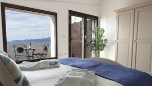 A bedroom with a bed, a view of the sea, a balcony with a table and chairs, and a potted plant. - Sea views in a tranquil area. Infinity saline pool. AC & WIFI (magomados)