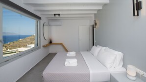 A modern bedroom with a large window, a bed with white linens, a bedside table, and a wall-mounted light. - Villa Orion Mykonos - Blue Views Mykonos Villas (Mykonos)