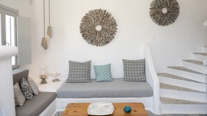 A modern interior with a white staircase, a grey sofa with patterned cushions, and two wall-mounted decor pieces. - Villa Orion Mykonos - Blue Views Mykonos Villas (Mykonos)