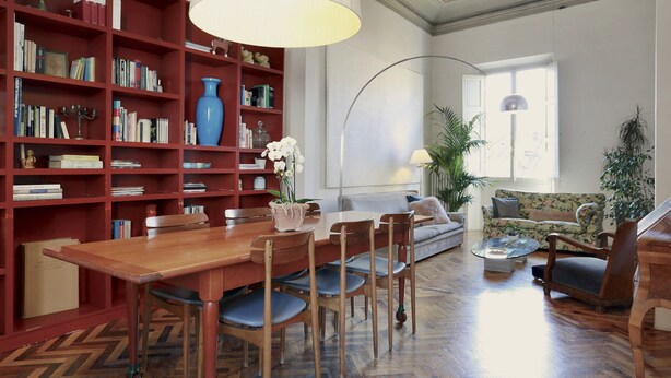 Ein geräumiges Wohnzimmer mit einem Holzespeisetisch, Stühlen, einem Bücherregal und einem Sofa.