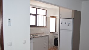 Una cocina con alacenas blancas, horno empotrado y refrigerador.