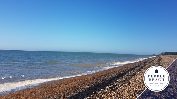 A pebble beach with a clear sky and calm sea.