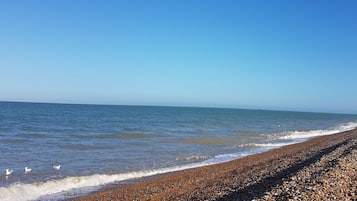 A pebble beach with a clear sky and calm sea.