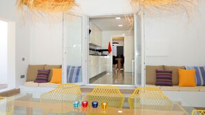 Uma sala de estar moderna com uma mesa de vidro, cadeiras amarelas e um sofá com almofadas coloridas.