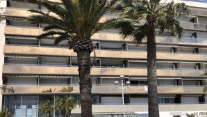 Un edificio de varios pisos con balcones, palmeras y un restaurante llamado "bistro régent" en la planta baja.
