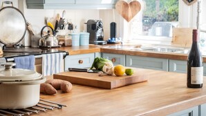 A kitchen counter with a cutting board, vegetables, a wine bottle, and a heart-shaped welcome sign. - Modern Cottage, big garden, AGA, Loch/Mountain Views. Cinema Room & Log Burner (Arrochar)