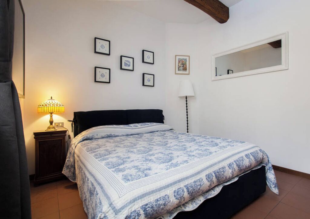 A bedroom with a bed, a nightstand, a lamp, and framed pictures on the wall.