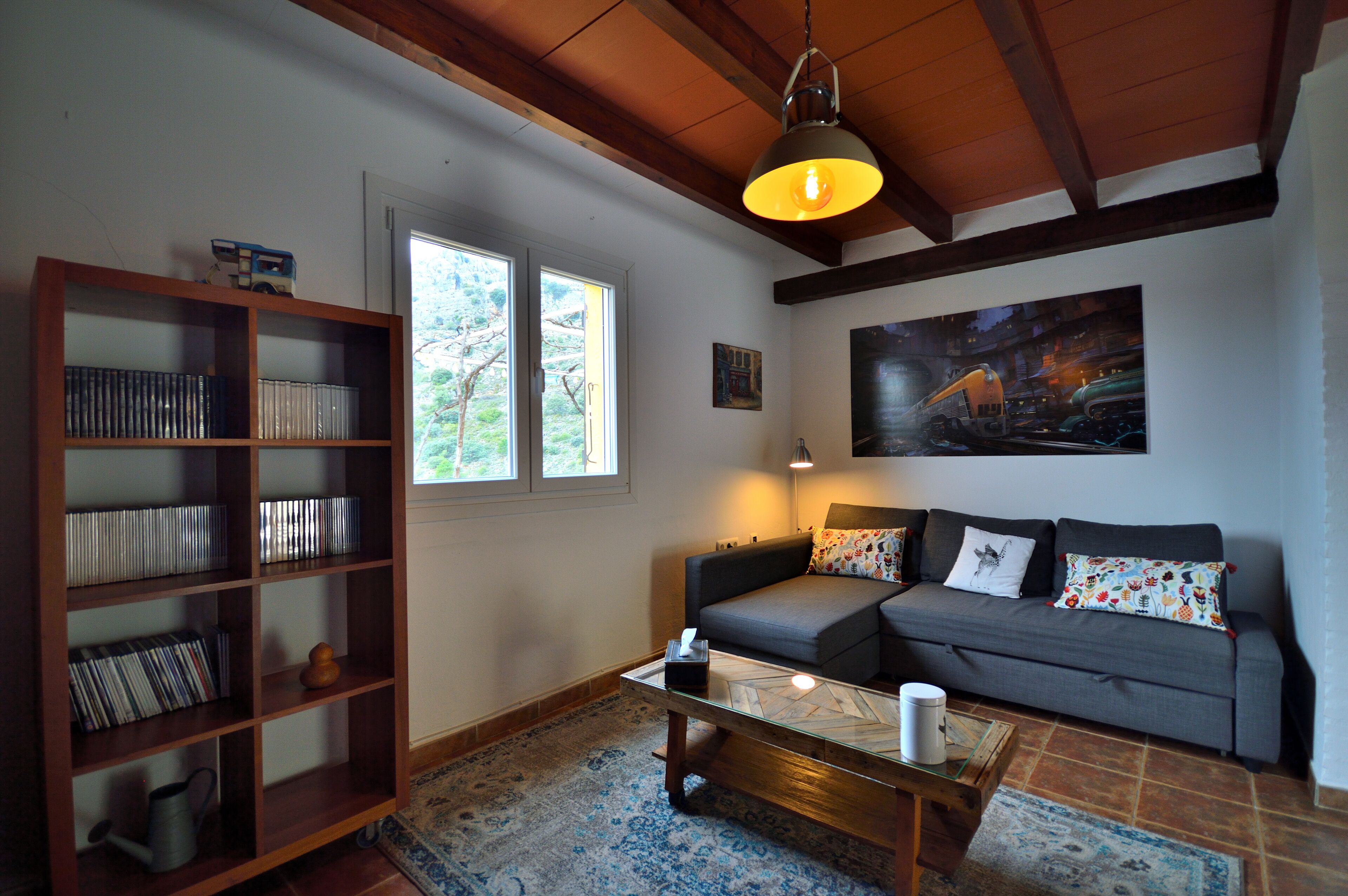A living room with a sofa, a coffee table, a bookshelf, and a painting on the wall.