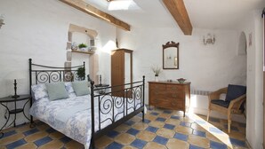 Quarto com cama, penteadeira, cadeira e espelho.