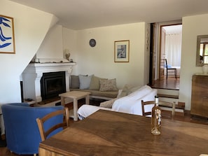 A living room with a fireplace, a sofa, a dining table, and a blue armchair.