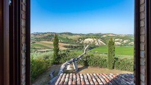 Un mur de pierres rustiques offrant une vue sur des collines verdoyantes et des vignobles.
