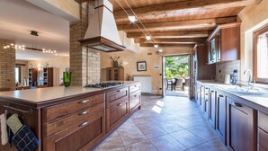 Une cuisine spacieuse avec des meubles en bois, un grand îlot central et une vue sur la terrasse extérieure.