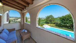 Un balcon avec vue sur une piscine et la campagne environnante.