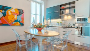 A modern kitchen with a wooden table, clear chairs, and a colorful painting on the wall. - PIAZZA DI SPAGNA APARTMENT (Roma)