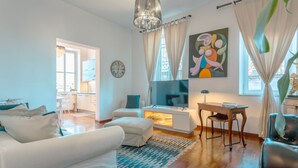 A modern living room with a sofa, ottoman, and a dining area with a table and chairs. - PIAZZA DI SPAGNA APARTMENT (Roma)