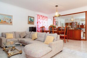 A living room with a sectional sofa, a glass coffee table, and a dining area with a wooden table and chairs. - Beautiful villa Ramos in San Antonio Bay with BBQ and large pool (Sant Josep de Sa Talaia / San Jose)