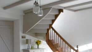 Ein Zimmer mit einem grünen Sofa, einem Holzstuhl, einer Treppe und einem weißen Schrank.