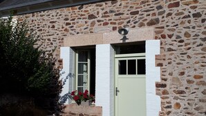 Ein Gebäude aus Stein mit Tür, Fenstern und einer kleinen Veranda.