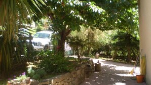 A paved pathway leading to a stone wall with a car parked nearby. - U vene e posa - the Pinzelli mountain.  (Lugo-Di-Nazza)