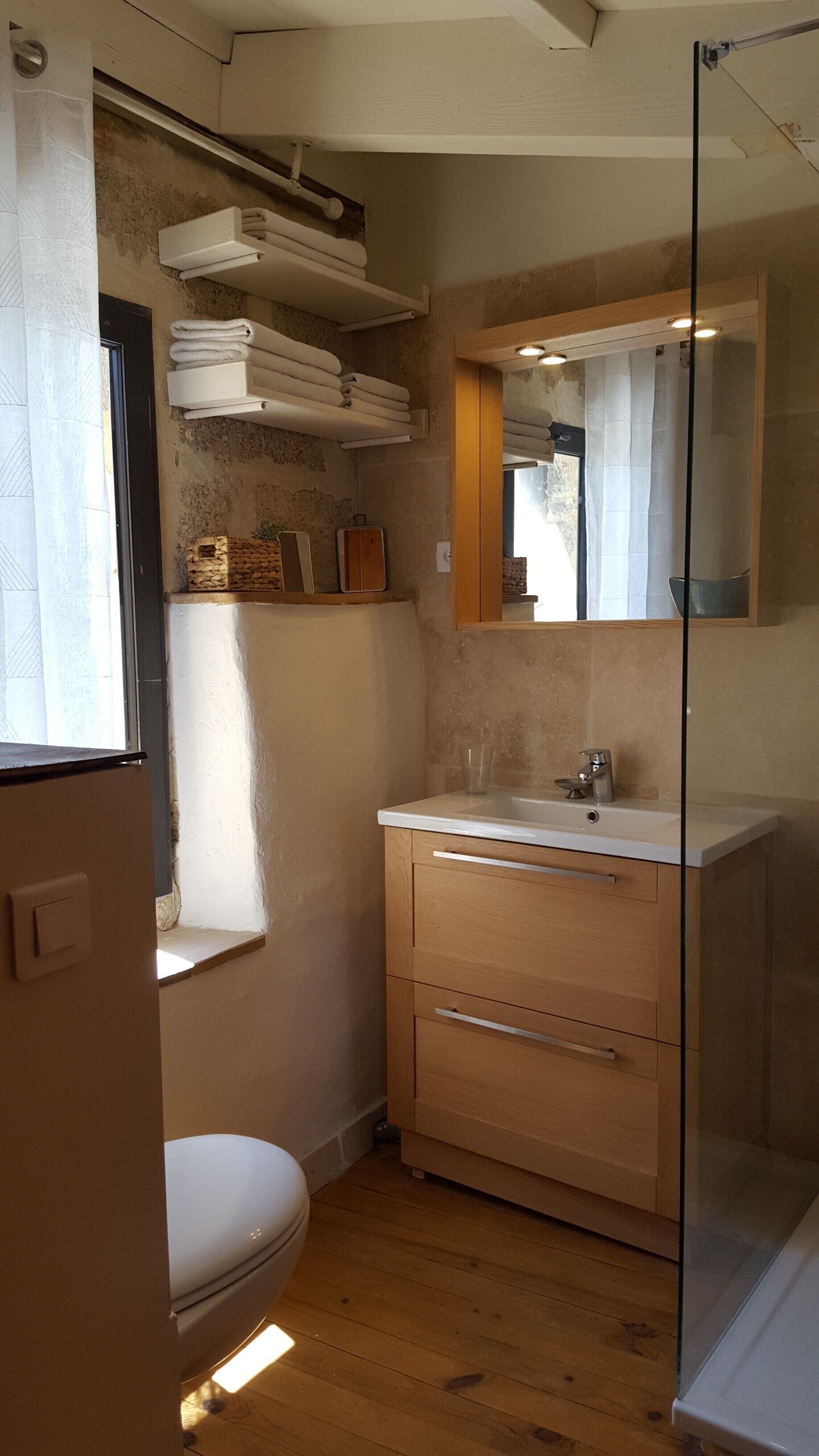 A compact bathroom with a toilet, a sink, and a glass shower enclosure.