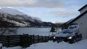 A car parked in front of a building with a view of a lake and mountains.