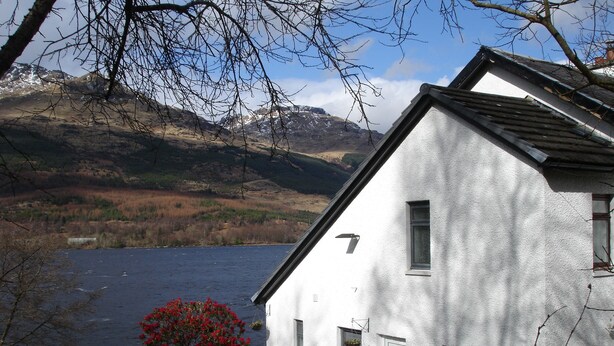 A white building with a sloped roof, a small window, and a door with a number plate.