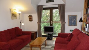 A living room with two red sofas, a wooden coffee table, a TV, and a large window with curtains. - Paradise in the Lake District. (Skelwith Bridge, Ambleside)